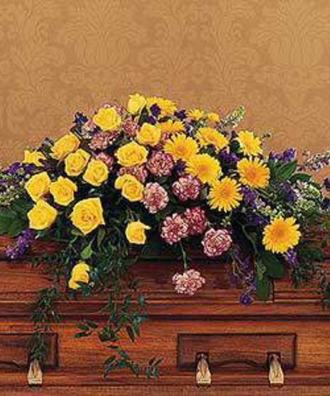 Casket spray of yellow and purple flowers with greenery.