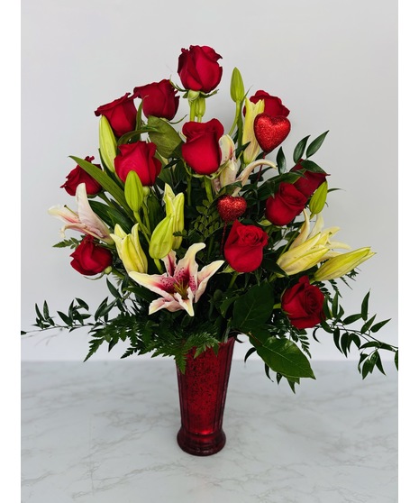 Stargazer lilies and red roses in a vase tied with red ribbon.